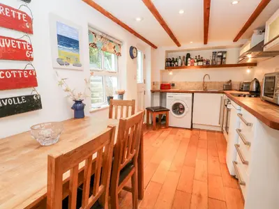 a kitchen with a long wooden table and chairs at Honeysuckle Cottage in St. Agnes