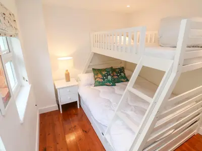 a white bunk bed with a couch in a room at Honeysuckle Cottage in St. Agnes
