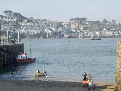 a group of people walking on the beach with a boat in the water at Fairmaiden in Polruan