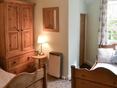 a bedroom with a bed and a dresser and a lamp at Fairmaiden in Polruan