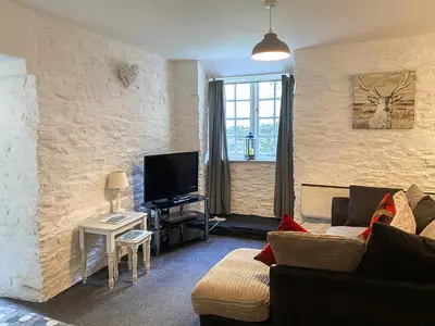 a living room with a couch and a flat screen tv at Carpenters Cottage - Cv17 in Liskeard