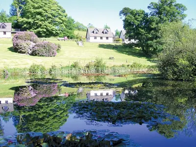 a reflection of a house in the water of a lake at Pencarrow - B6521 in Saint Cleer