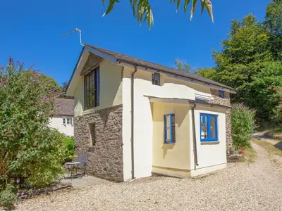 a small white house with blue windows on a gravel driveway at Alyshan in Merrymeet