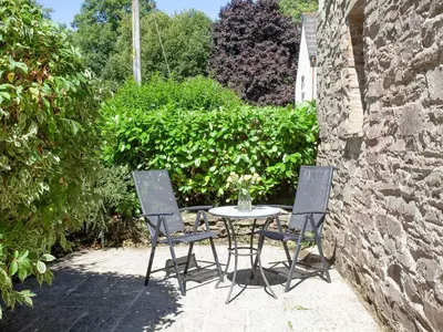 a table and two chairs sitting next to a stone wall at Alyshan in Merrymeet
