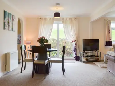 a living room with a table and chairs and a television at Talland Bay in Saint Cleer