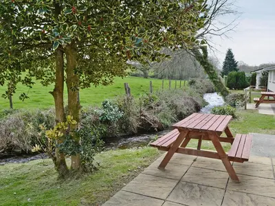 a wooden picnic table sitting next to a tree at Seaton in Saint Cleer