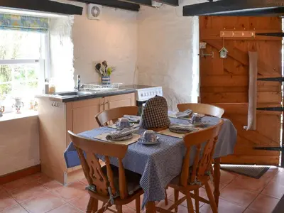 a kitchen with a table with chairs and a sink at Trekeive Cottage in Saint Cleer