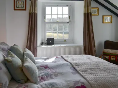 a bedroom with a large bed and a window at Trekeive Cottage in Saint Cleer