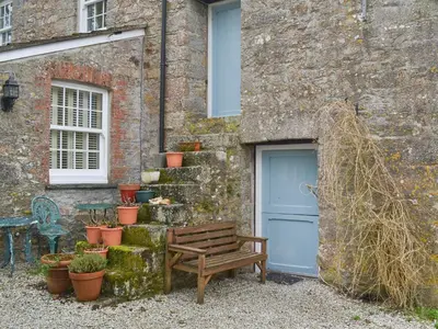 a wooden bench next to a building with a blue door at Trekeive Cottage in Saint Cleer