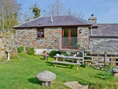 a stone house with a picnic table in the yard at Tripp Cottage in Saint Neot