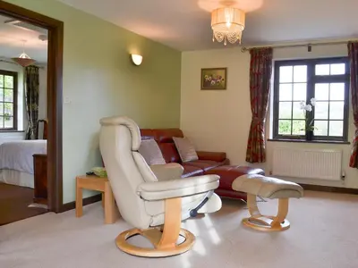 a living room with a chair and a couch at Tripp Cottage in Saint Neot