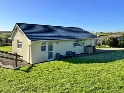 a small white house with a grass yard at Badgers Drift in Doublebois