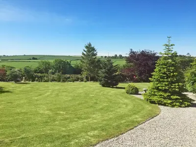 a large grassy yard with trees and a pathway at Badgers Drift in Doublebois