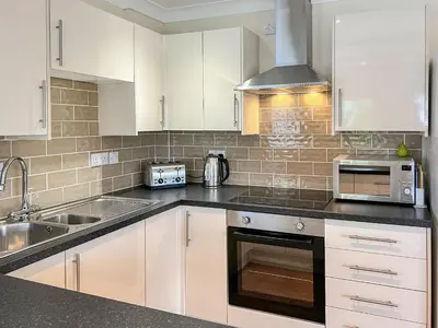 a kitchen with white cabinets and a sink and a microwave at Badgers Drift in Doublebois