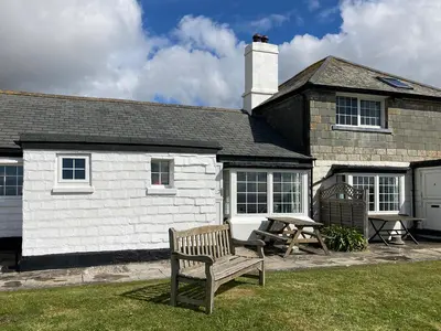 a bench in front of a house with a picnic table at 3 The Coastguards in Downderry