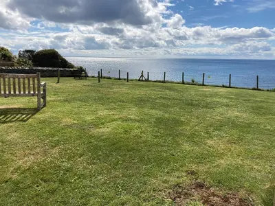 a park with a bench in the grass near the water at 3 The Coastguards in Downderry