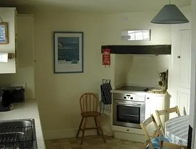 a kitchen with a stove and a chair in it at 3 The Coastguards in Downderry