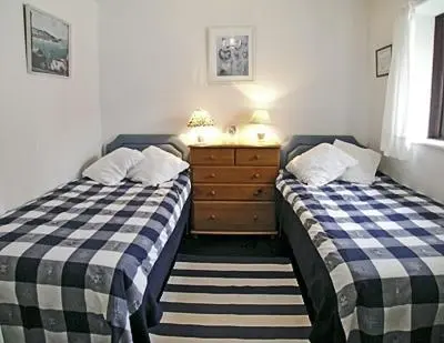 a bedroom with two beds and a dresser at 3 The Coastguards in Downderry