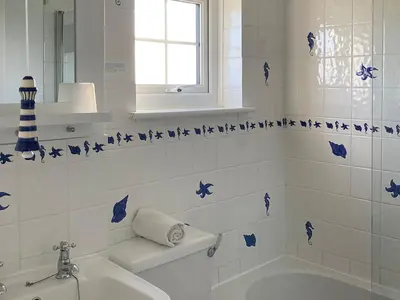 a bathroom with a tub and a sink with blue butterflies at 3 The Coastguards in Downderry