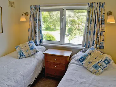a bedroom with two twin beds and a window at Coastguard Cottage in Downderry