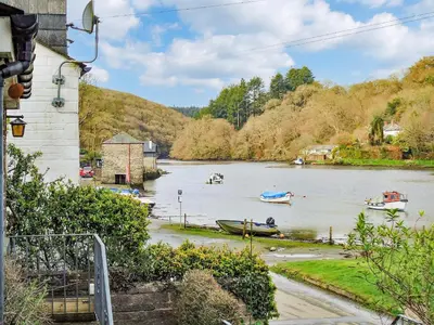 a river with boats in the water near a house at Florin Cottage in Lerryn