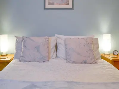 a white bed with two pillows and two lamps at Trenay Barns Cottage in Warleggan