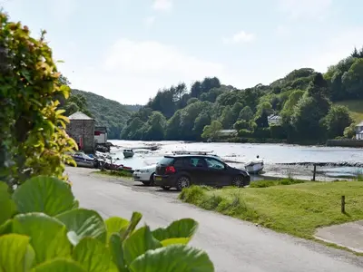 a group of cars parked next to a river with boats at Watercolour Cottage in Lerryn