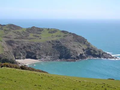 a beach on a hill next to the ocean at Watercolour Cottage in Lerryn