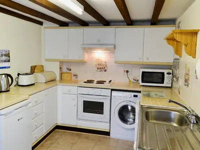 a kitchen with white cabinets and a washing machine at Watercolour Cottage in Lerryn