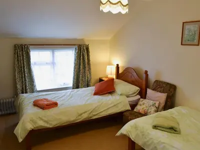 a bedroom with two beds and a window at Watercolour Cottage in Lerryn