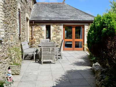 a patio with two chairs and a wooden door at Penty Rosen in Pentewan