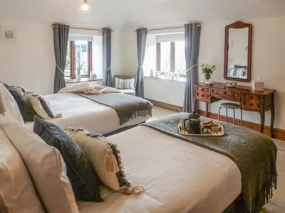 a bedroom with two beds and a desk and a mirror at Anneth Lowen in Pentewan