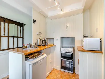 a kitchen with white cabinets and a counter top at Memory Cottage in Mevagissey