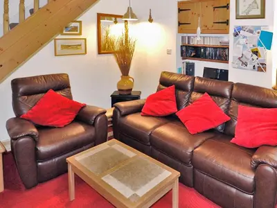 a living room with brown leather couches and red pillows at Sea Haven - Tho in Gorran Haven