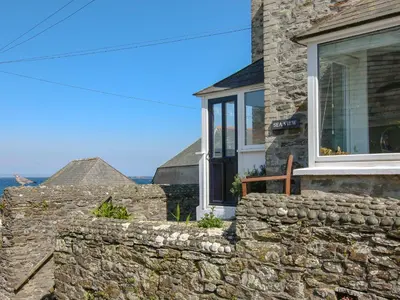 a stone house with a window and a stone wall at Seaview in Gorran Haven
