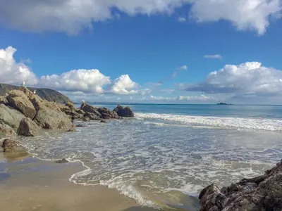 a beach with rocks and the ocean on a cloudy day at Seaview in Gorran Haven