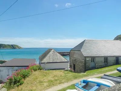 a house and a boat in front of the water at Seaview in Gorran Haven