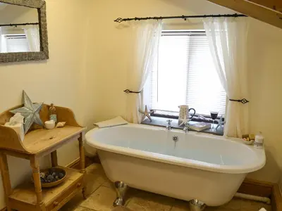 a bath tub in a bathroom with a window at The Old Wash House in Pentewan