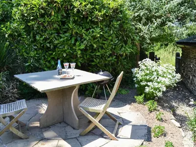 a table with two chairs and a bottle and glasses on it at The Old Wash House in Pentewan