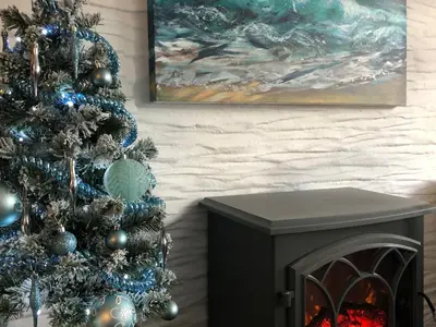 a christmas tree and a fireplace in a living room at Puffin Burrow in Portmellon