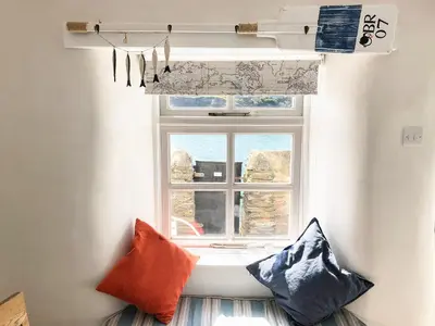 a window with two pillows sitting in front of it at Puffin Burrow in Portmellon