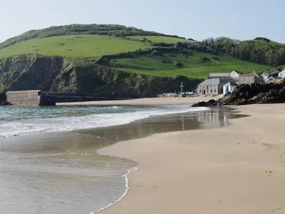 a sandy beach with houses and a hill at The Gables in Gorran Haven