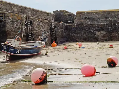 a boat sitting on the beach next to a wall at The Gables in Gorran Haven