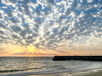 a cloudy sky over the ocean with a pier at The Gables in Gorran Haven