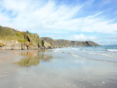 a beach with a reflection in the water at The Gables in Gorran Haven