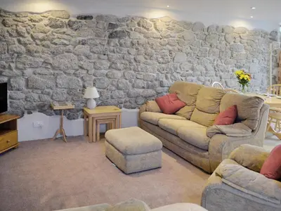 a living room with a couch and a stone wall at The Old Coach House in St Austell