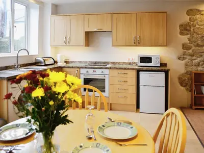 a kitchen with a table with a vase of flowers on it at The Old Coach House in St Austell