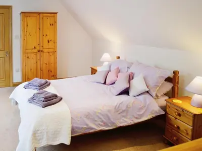 a bedroom with a bed with white sheets and pink pillows at The Old Coach House in St Austell