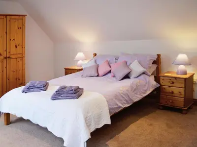 a bedroom with a bed with two night stands and two lamps at The Old Coach House in St Austell