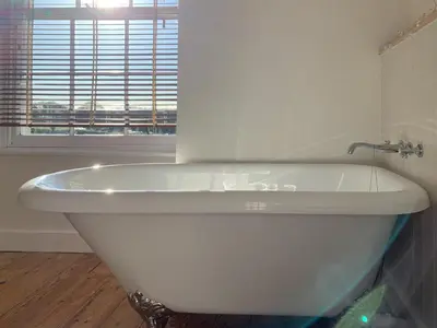 a white bath tub in a bathroom with a window at Gewans Farm Cottage in St Austell
